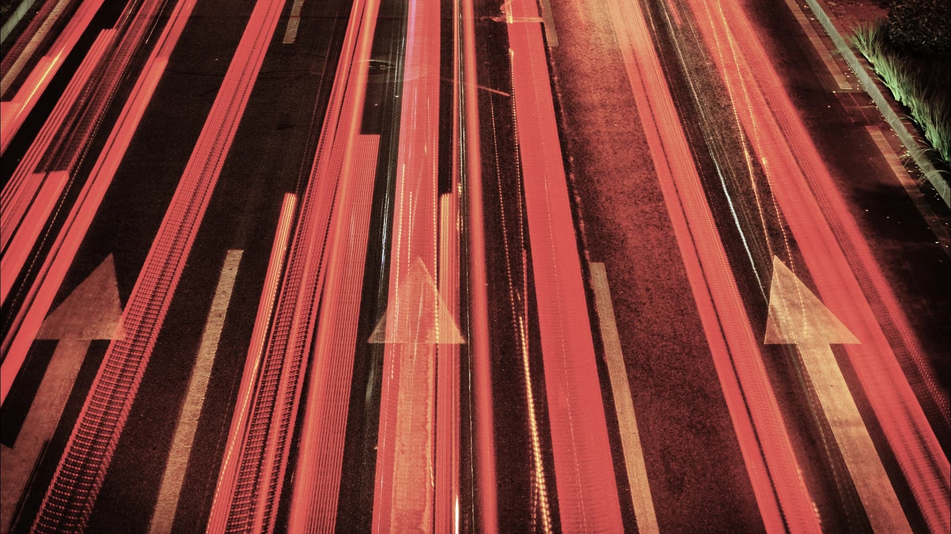 Long-exposure light trails and arrows on a multi-lane road at night.